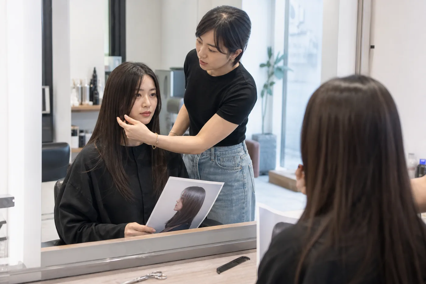 Profissional e cliente conferindo o comprimento do cabelo liso